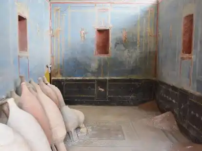 Ein Raum mit blauen Wänden und gemalten weiblichen Figuren ist in Pompeji freigelegt worden.