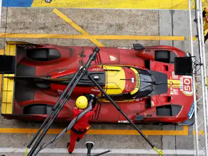 Mechaniker betanken das Auto des Teams Ferrari.