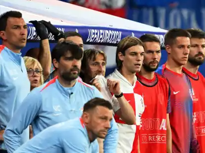 Kroatiens Luka Modric (M) und seine Teamkollegen schauen vom Spielfeldrand zu.