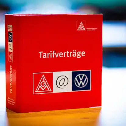 Auf dem Tisch liegt ein Ordner mit der Aufschrift „Tarifverträge“. Nach einer Marathonsitzung einigten sich VW-Führung und IG Metall auf einen Kompromiss.