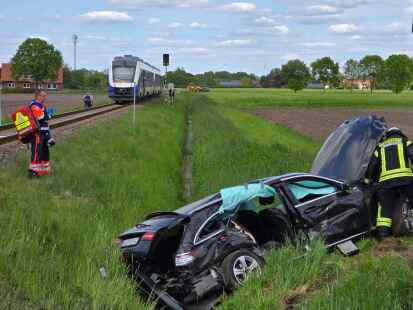 Bahnunfall in Rieste: Einsatzkräfte arbeiten an einem stark beschädigten Auto.