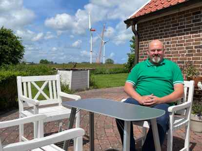 Timo Ostermann sitzt auf seiner Terrasse in Zissenhausen (Wangerland). Die Windräder des Windparks Pievens sind nur knapp 500 Meter von seinem Grundstück entfernt.