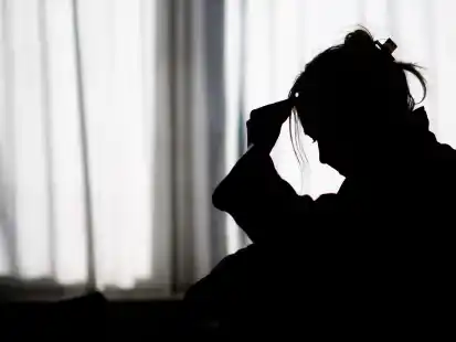 ILLUSTRATION - Die Silhouette einer Frau zeichnet sich vor einer hellen Fensterfront ab (gestellte Szene). (zu dpa: «DAK-Erhebung: Hoher Arbeitsausfall wegen kranker Seele») +++ dpa-Bildfunk +++