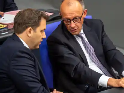 Bundeskanzler Friedrich Merz (CDU, r.) spricht mit Lars Klingbeil (SPD), Bundesminister der Finanzen, im Bundestag.