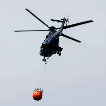 Ein Löschhubschrauber der Bundespolizei fliegt über dem Zeithainer Tagebau und nimmt Wasser auf, um den Waldbrand Gohrischheide zu bekämpfen.