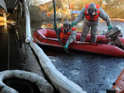 Angehörige des Technischen Hilfswerks (THW) saugen den Ölfilm von der Wasseroberfläche des Friedeburger Tiefs bei Zetel (Archivbild).