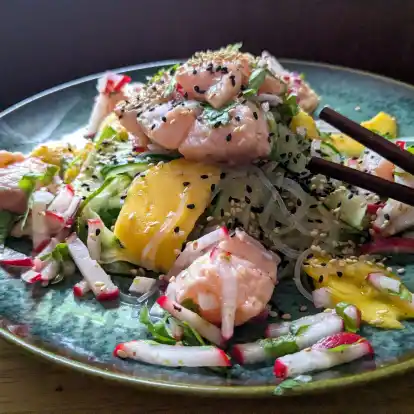 Der Glasnudelsalat mit Lachs-Ceviche wird mit gerösteten weißen und schwarzen Sesamkörnchen getoppt.