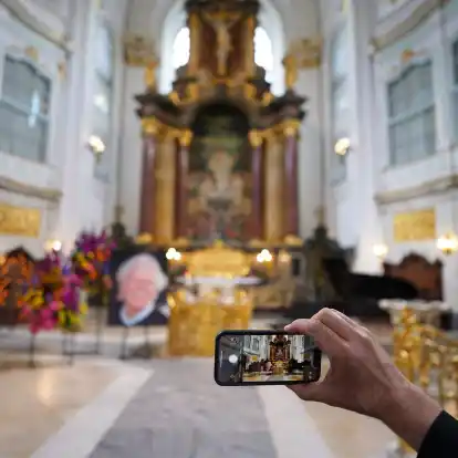 Ein Besucher macht zu Beginn der Trauerfeier ein Foto mit einem Smartphone.