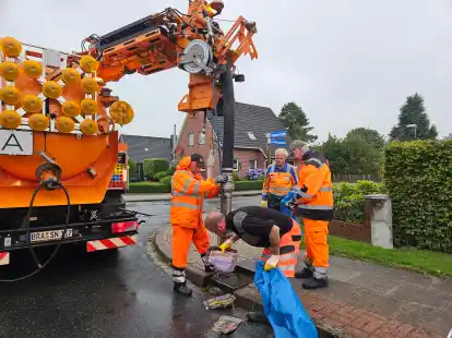 Mitarbeiter des Bauhofs der Stadt Nordenham holen illegal entsorgte Zeitungen aus einem Regenwasserschacht in Großensiel.