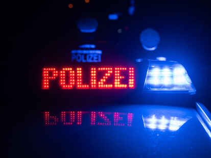 Zwei Polizisten stehen im Rahmen eines Fototermins vor einem Polizeifahrzeug (gestellte Szene). (Symbolbild)