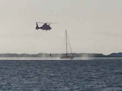 Aufnahme vom Seenotrettungsboot „Fritz Thieme“ aus: Mit dem Hubschrauber wird ein Notfallsanitäter auf dem Segelboot absetzt
