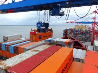 Am Bug der „Wilhelmshaven Express“ wehen aus Anlass des Erstanlaufs in Wilhelmshaven bunte Wimpel, während das Team von Eurogate längst voll mit dem Umschlag der Boxen beschäftigt ist.