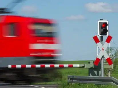 Ein Zug fährt an einem geschlossenem Bahnübergang vorbei. (Symbolbild)