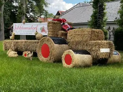 Hier geht's lang: Auf das Dorfjubiläum weist ein Stroh-Trecker-Gespann am Ortseingang hin.